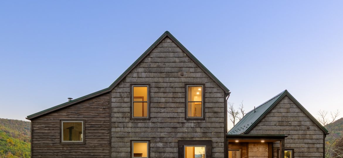 Front view of the cabin at dusk with windows illuminated.