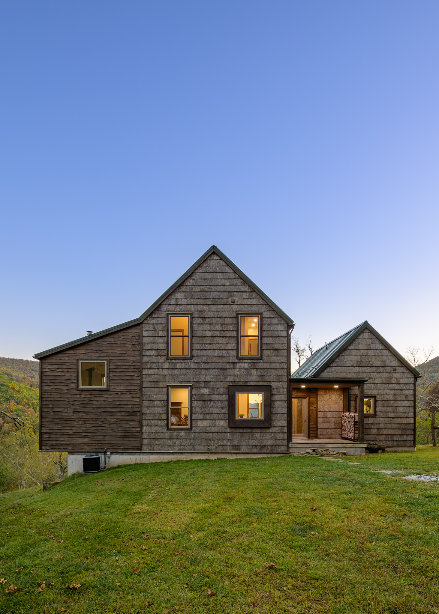 Front view of the cabin at dusk with windows illuminated.